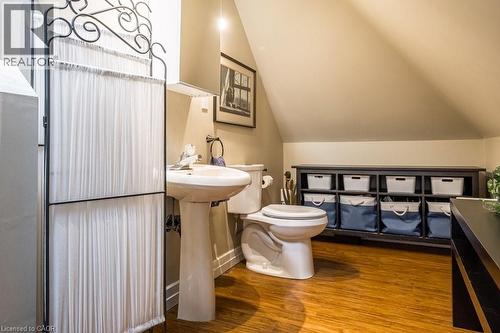 This bathroom features a pedestal sink, a toilet, and hardwood flooring - 36 Eastbourne Avenue, Hamilton, ON - Indoor Photo Showing Bathroom