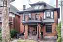 The property presents a brick facade with a covered front porch and a second-level balcony, featuring dark-framed windows and a bay window design - 36 Eastbourne Avenue, Hamilton, ON  - Outdoor With Balcony 