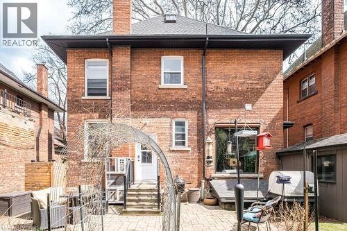 The property features a brick exterior, a paved patio area, and a white rear entrance door with steps leading to the yard - 36 Eastbourne Avenue, Hamilton, ON - Outdoor With Deck Patio Veranda With Exterior