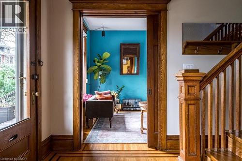 Entryway featuring hardwood floors with a border inlay, a staircase with wooden newel post and balusters, and a solid wood door with a glass panel - 36 Eastbourne Avenue, Hamilton, ON - Indoor Photo Showing Other Room