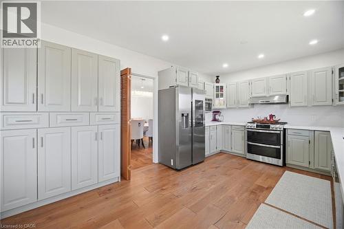 The kitchen features extensive light-colored cabinetry, stainless steel appliances, and wood flooring - 38 Leclaire Street, Hamilton, ON - Indoor Photo Showing Kitchen