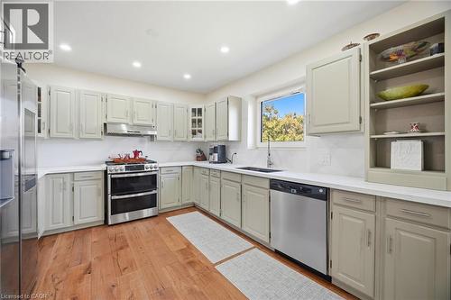 The kitchen features hardwood floors, light-colored cabinetry, white countertops, and stainless steel appliances - 38 Leclaire Street, Hamilton, ON - Indoor Photo Showing Kitchen With Stainless Steel Kitchen