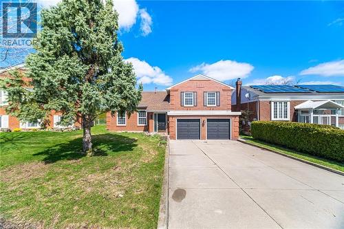 The property features a brick facade, a two-car garage, and a paved driveway - 38 Leclaire Street, Hamilton, ON - Outdoor