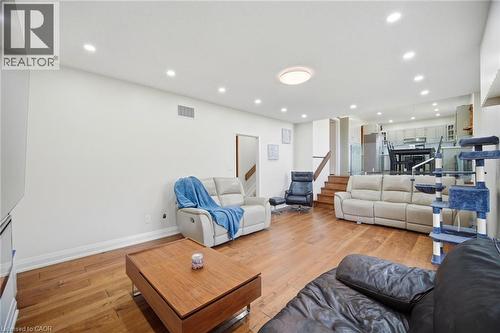 The property features hardwood flooring, recessed lighting, and a visible staircase with a wooden handrail - 38 Leclaire Street, Hamilton, ON - Indoor Photo Showing Other Room