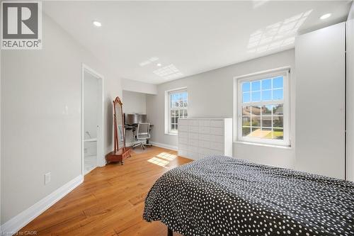 This room features hardwood flooring, recessed lighting, and two windows providing natural light - 38 Leclaire Street, Hamilton, ON - Indoor Photo Showing Bedroom