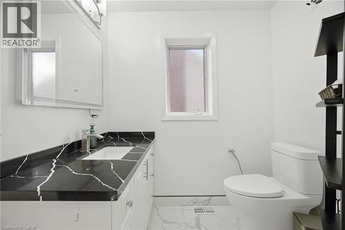 Bathroom featuring a vanity with a black countertop, a white rectangular sink, and a framed mirror with integrated lighting - 38 Leclaire Street, Hamilton, ON - Indoor Photo Showing Bathroom