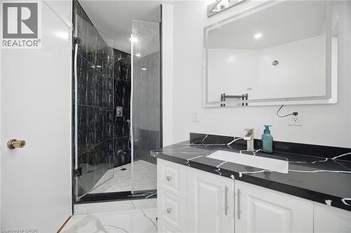 The bathroom features a sleek vanity with a dark countertop and an undermount sink, complemented by a modern faucet - 38 Leclaire Street, Hamilton, ON - Indoor Photo Showing Bathroom