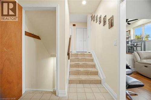 Entryway featuring tiled flooring, a staircase with a wooden handrail, and a storage area - 38 Leclaire Street, Hamilton, ON - Indoor Photo Showing Other Room