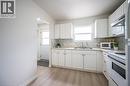 Bright kitchen featuring white cabinetry, light countertops, a stainless steel sink, and wood-finish flooring - 212 Westcourt Place, Waterloo, ON  - Indoor Photo Showing Kitchen With Double Sink 