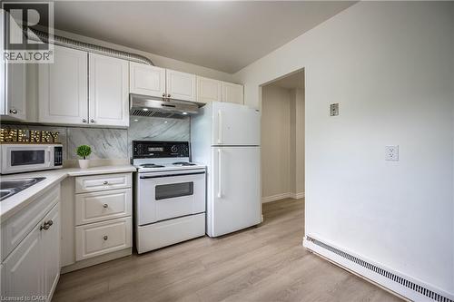 Kitchen featuring white cabinetry, a light-toned countertop, and a patterned backsplash - 212 Westcourt Place, Waterloo, ON - Indoor Photo Showing Kitchen