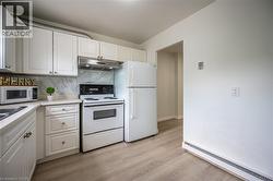 Kitchen featuring white cabinetry, a light-toned countertop, and a patterned backsplash - 