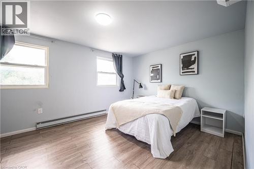 Bedroom featuring wood-finish flooring, two large windows, a flush-mount ceiling light, and baseboard heating - 212 Westcourt Place, Waterloo, ON - Indoor Photo Showing Bedroom