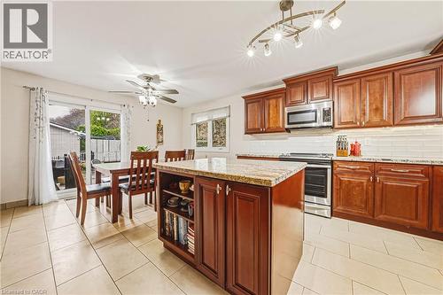 Kitchen featuring stainless steel appliances, a center island, light stone countertops, backsplash, and light tile patterned floors - 24 Hildegard Drive, Hamilton, ON - Indoor Photo Showing Kitchen