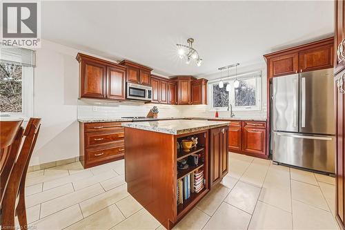 Kitchen with stainless steel appliances, a kitchen island, light stone countertops, light tile patterned floors, and open shelves - 24 Hildegard Drive, Hamilton, ON - Indoor Photo Showing Kitchen