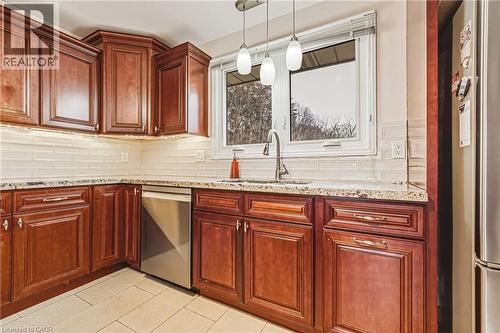Kitchen featuring stainless steel appliances, light stone countertops, tasteful backsplash, decorative light fixtures, and light tile patterned floors - 24 Hildegard Drive, Hamilton, ON - Indoor Photo Showing Kitchen