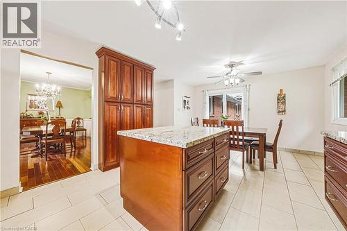 Kitchen with light tile patterned floors, light stone counters, suspended lighting, and a kitchen island - 24 Hildegard Drive, Hamilton, ON - Indoor