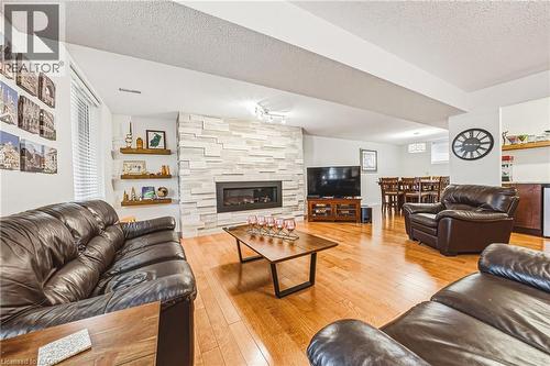 Living room with a textured ceiling, light wood-type flooring, a fireplace, and plenty of natural light - 24 Hildegard Drive, Hamilton, ON - Indoor Photo Showing Living Room With Fireplace