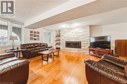 Living area with a textured ceiling, light wood-style flooring, and a large fireplace - 24 Hildegard Drive, Hamilton, ON - Indoor Photo Showing Living Room With Fireplace