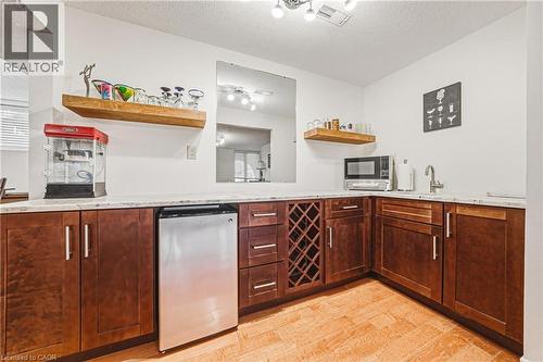 Bar featuring open shelves, a textured ceiling, light wood-style flooring, stainless steel fridge, and light stone counters - 24 Hildegard Drive, Hamilton, ON - Indoor Photo Showing Kitchen