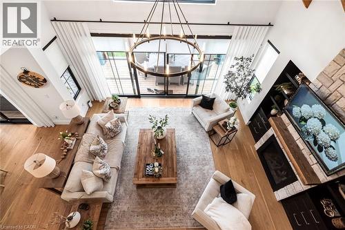 Spacious living area featuring high ceilings, light wood-finish flooring, and a large multi-panel glass door leading to an outdoor space - 253 Central Avenue, Grimsby, ON 
