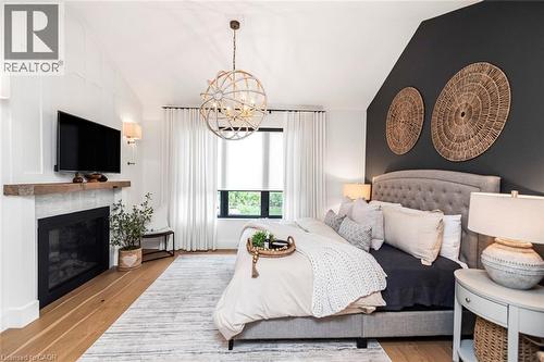 Bedroom featuring a vaulted ceiling with exposed beam-look detailing and a prominent fireplace with a rustic wood mantel - 253 Central Avenue, Grimsby, ON 