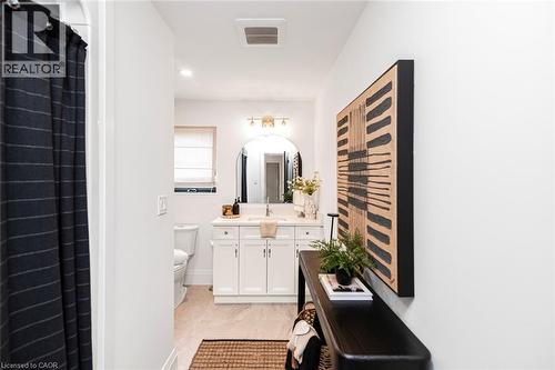 Contemporary bathroom vanity with a single basin sink, white cabinetry, and a rectangular mirror - 253 Central Avenue, Grimsby, ON 