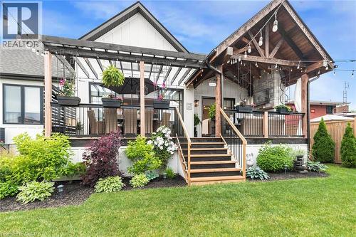 Expansive backyard featuring a manicured lawn, multi-level deck with black railing, and mature landscaping - 253 Central Avenue, Grimsby, ON 