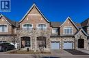 The property features an appealing exterior facade with a combination of brick and stone, a prominent front entrance, and two distinct garage doors - 2453 Village Common, Oakville, ON  - Outdoor With Facade 