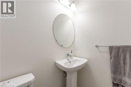 Well-appointed bathroom featuring a pedestal sink, an oval mirror, and overhead lighting - 2453 Village Common, Oakville, ON - Indoor Photo Showing Bathroom