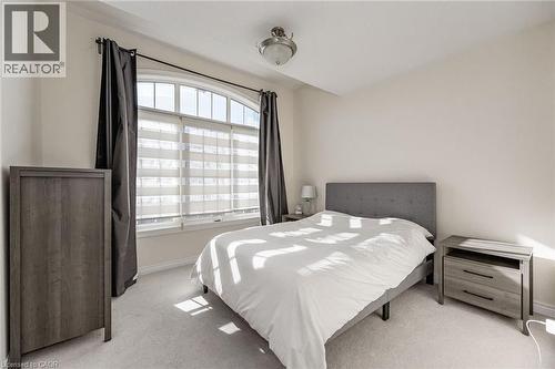 This room features a large arched window with blinds and dark curtains, light-colored walls, and carpeting - 2453 Village Common, Oakville, ON - Indoor Photo Showing Bedroom