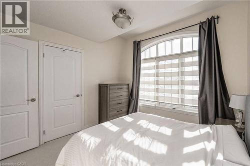 The property features an arched window with blinds and drapes, two panel doors, and a ceiling light fixture - 2453 Village Common, Oakville, ON - Indoor Photo Showing Bedroom