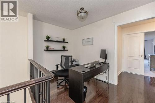 This functional space features rich hardwood flooring, light-colored walls, and a staircase with dark metal spindles and a wooden handrail - 2453 Village Common, Oakville, ON - Indoor Photo Showing Office
