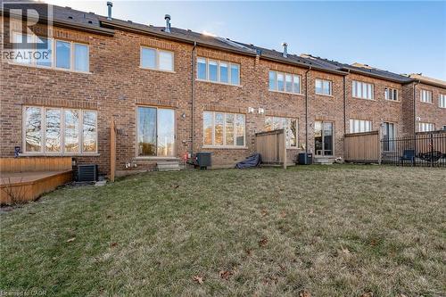 The property features a brick exterior with a well-maintained lawn and a wooden deck - 2453 Village Common, Oakville, ON - Outdoor With Exterior