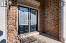 The property features a brick exterior, a double door entry with glass panels, and an exterior light fixture - 2453 Village Common, Oakville, ON  - Outdoor With Exterior 