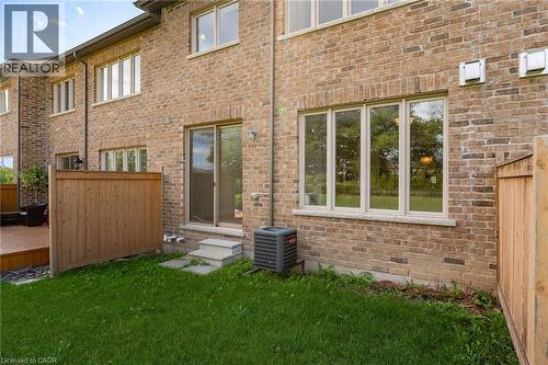 The property features a brick exterior, a well-maintained lawn, and a wooden fence - 2453 Village Common, Oakville, ON - Outdoor With Exterior