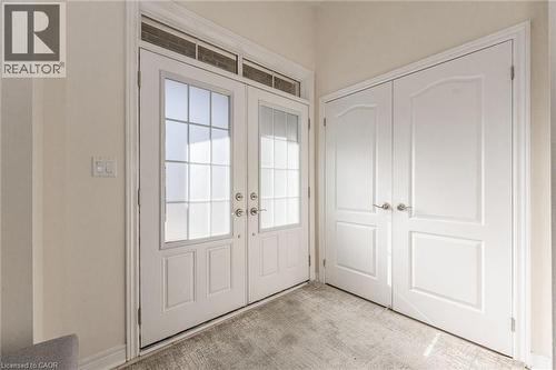 The entryway features double doors with frosted glass panels and an overhead transom window, complemented by a pair of solid white doors with arched paneling - 2453 Village Common, Oakville, ON - Indoor Photo Showing Other Room