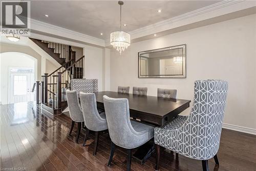 Formal dining area featuring hardwood floors, a dark wood dining table, and a tiered crystal chandelier - 2453 Village Common, Oakville, ON - Indoor Photo Showing Dining Room