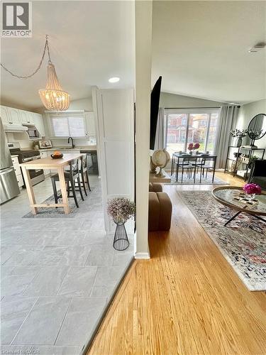 This property features a kitchen with white cabinetry, a kitchen island, and a beaded chandelier - 241 Thorner Drive, Hamilton, ON - Indoor