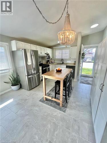 The kitchen features a stainless steel refrigerator, white cabinetry, and light-toned tile flooring - 241 Thorner Drive, Hamilton, ON - Indoor Photo Showing Dining Room
