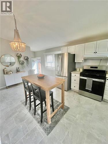 The kitchen features light-toned tiled flooring, white cabinetry, and stainless steel appliances including a refrigerator and a range - 241 Thorner Drive, Hamilton, ON - Indoor