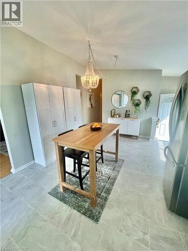 This inviting space features a light-colored tile floor, a prominent wooden high-top table, and a decorative chandelier - 241 Thorner Drive, Hamilton, ON - Indoor Photo Showing Other Room