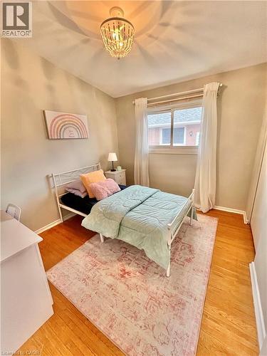 The room features hardwood floors and a window with white curtains, allowing for natural light - 241 Thorner Drive, Hamilton, ON - Indoor Photo Showing Bedroom
