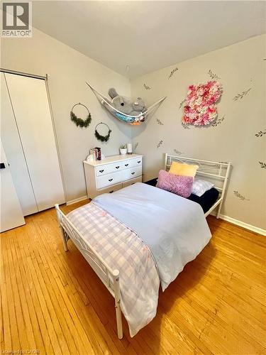 This room features hardwood flooring, light-colored walls, and a white wardrobe with sliding doors - 241 Thorner Drive, Hamilton, ON - Indoor Photo Showing Bedroom