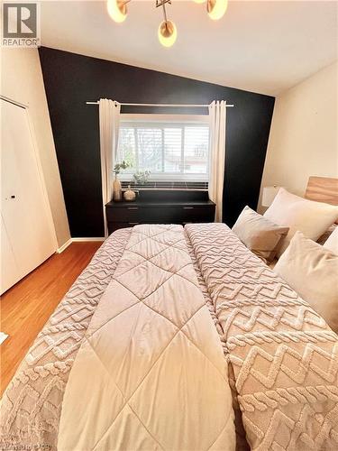 The property features hardwood flooring, a window with blinds, and a modern light fixture - 241 Thorner Drive, Hamilton, ON - Indoor Photo Showing Bedroom