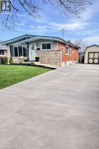 The property features a brick and stone facade, a well-maintained lawn, and a wide paved driveway - 241 Thorner Drive, Hamilton, ON - Outdoor