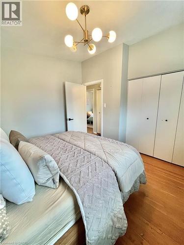 The room features hardwood floors, a contemporary ceiling light fixture, and built-in closet storage - 241 Thorner Drive, Hamilton, ON - Indoor Photo Showing Bedroom