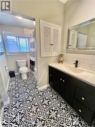 Bathroom featuring patterned floor tiles, a black vanity with a white countertop and gold hardware, and a mirrored wall cabinet - 241 Thorner Drive, Hamilton, ON - Indoor Photo Showing Bathroom