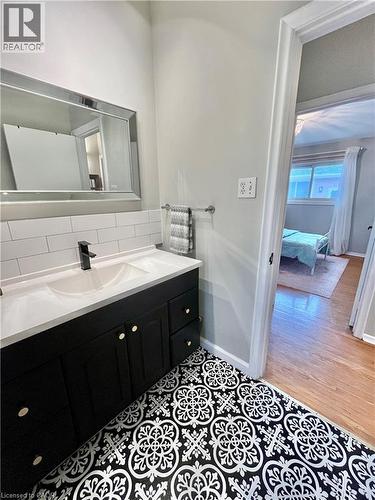 The bathroom features a modern vanity with a dual sink and a sleek black finish, complemented by a large framed mirror - 241 Thorner Drive, Hamilton, ON - Indoor Photo Showing Bathroom