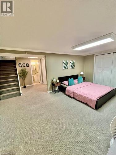 This spacious room features neutral-toned carpeting, a stairway with carpeted treads, and a white bi-fold closet - 241 Thorner Drive, Hamilton, ON - Indoor