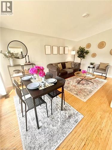 Living and dining areas featuring light-toned walls, hardwood flooring, and a round mirror - 241 Thorner Drive, Hamilton, ON - Indoor
